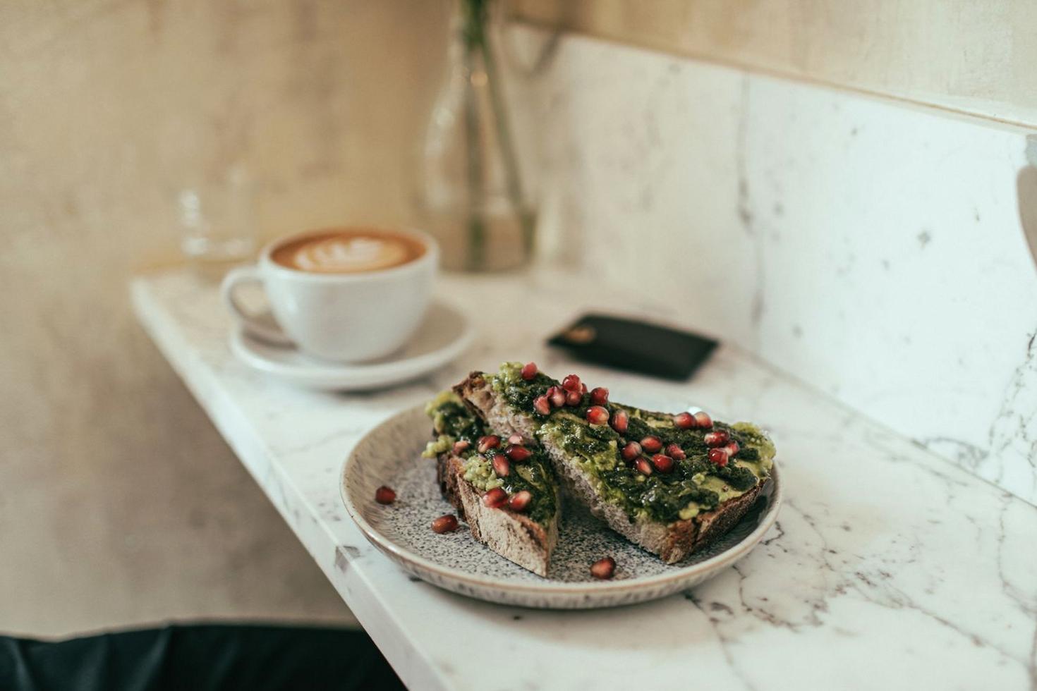 Fresh vegan avocado toast with pomegranate seeds and coffee